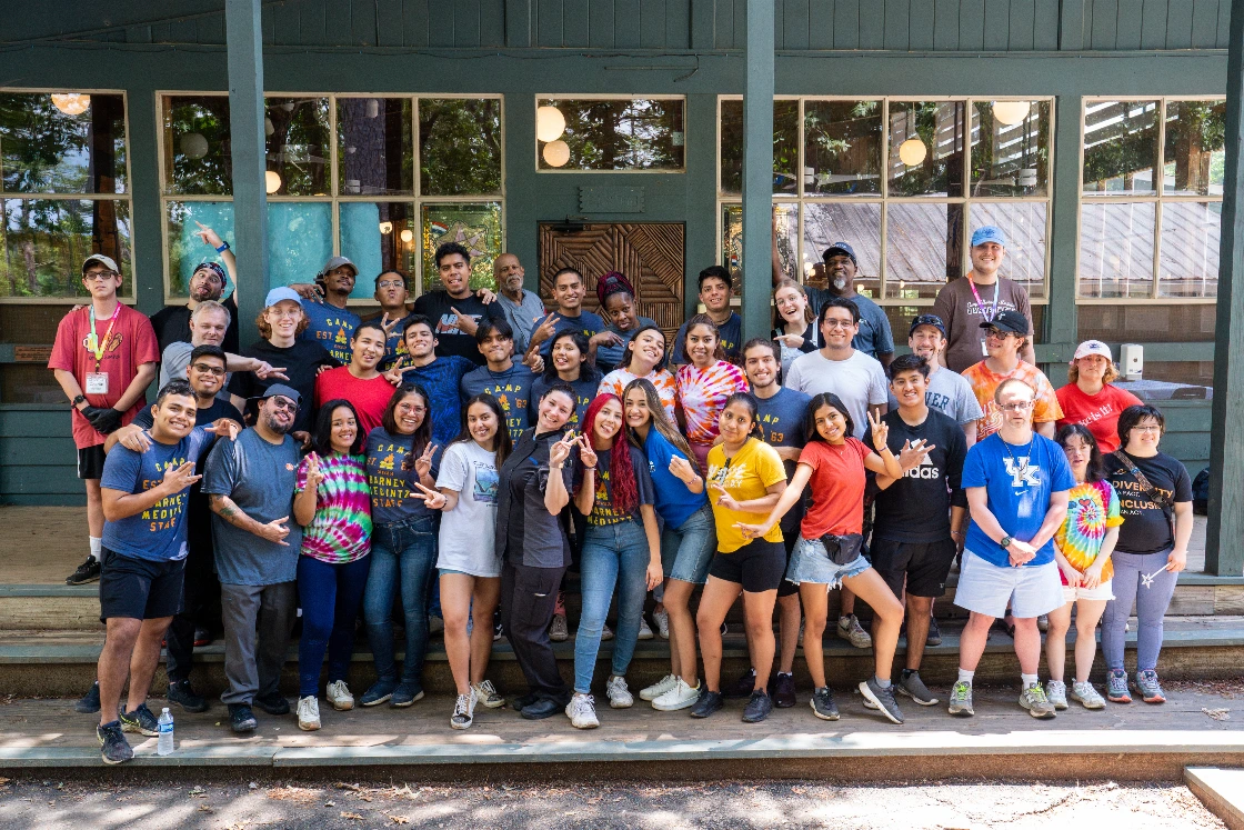A large group of campers and staff gathered together outside a camp building